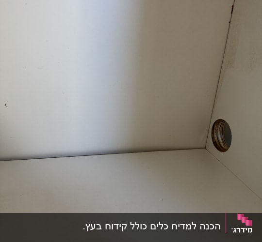 חור קדוח בחלקו הפנימי של ארון עץ להעברת צנרת